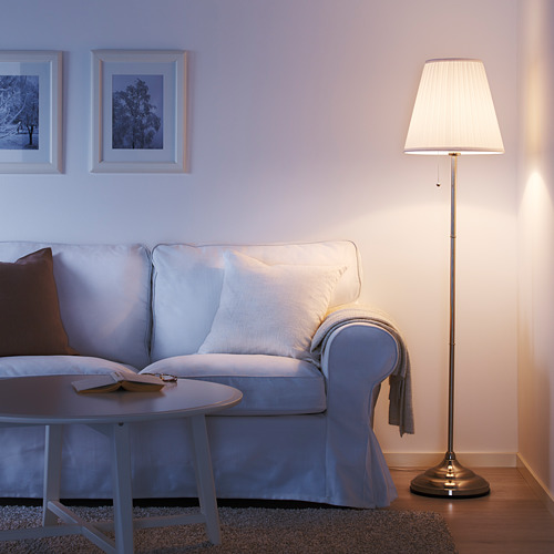 Acogedora sala de estar con lámpara ÅRSTID azul claro, pantalla blanca, que proporciona una luz suave cerca de un sofá azul claro y una mesa de café.