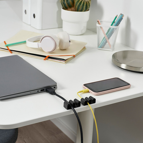 Escritorio de oficina con computadora portátil, carga de teléfono con soportes de cable KALKSTUFF que mantienen los cables ordenados.