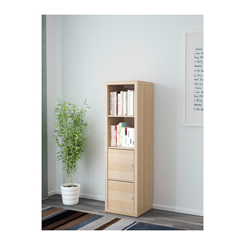 Mueble de almacenaje de madera KALLAX con estantes y cajones adosados a la pared, donde se encuentran libros y una cajonera debajo.