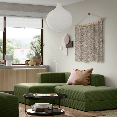 Sala de estar moderna con sofá JÄTTEBO verde, armario de madera, lámpara colgante, arte de pared y mesa auxiliar con libros y jarrón.
