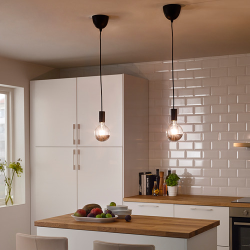 Dos luces colgantes SUNNEBY sobre la isla de la cocina con fruta, platos y plantas.
