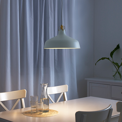 Comedor moderno con lámpara, mesa, sillas y cristalería RANARP. La iluminación suave crea un ambiente acogedor.