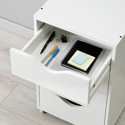 Cajonera blanca con cuatro compartimentos. Cajón superior abierto, con material de oficina como bolígrafos, clips y cuadernos. Ruedas robustas para facilitar el movimiento.