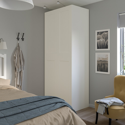 Dormitorio moderno con armario PAX blanco, cama, arte y silla amarilla.