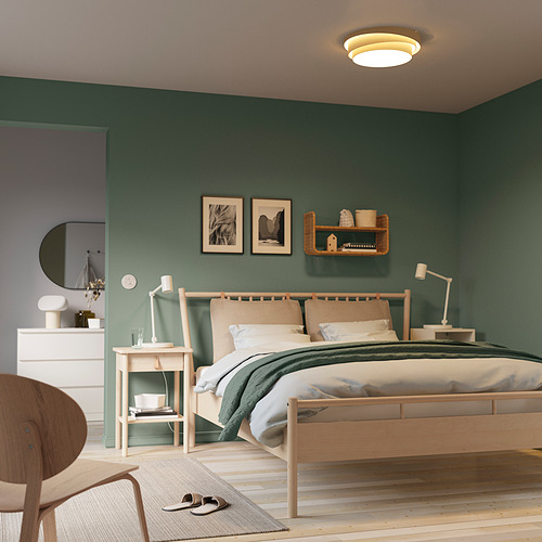 Dormitorio moderno verde con muebles de madera clara. Cama grande con ropa de cama blanca y verde, lámpara NÖSUND, decoración minimalista, tocador, espejo, silla.