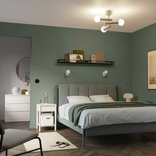 Dormitorio moderno con paredes verdes, lámpara de techo blanca y muebles blancos.