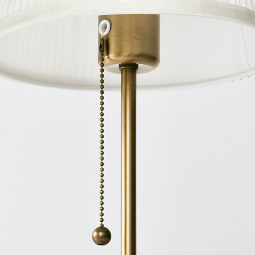 Detalle de lámpara dorada con cadena de tiro para interruptor, pantalla blanca.