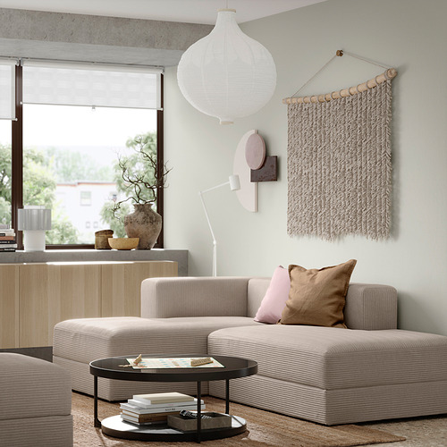 Sala de estar moderna con sofá seccional JÄTTEBO beige, lindos cojines, decoración de pared colgante y una gran ventana.