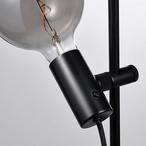 Primer plano de una lámpara moderna con bombilla grande, elegante soporte negro y junta ajustable.