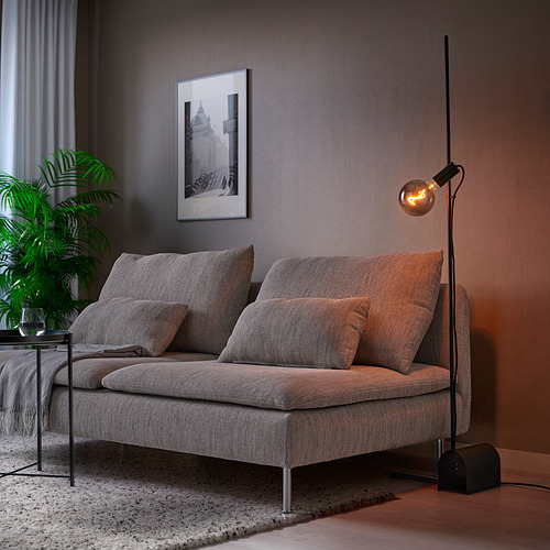 Sala de estar moderna con lámpara de pie HÅRSLINGA gris, iluminación tenue y silla acolchada.