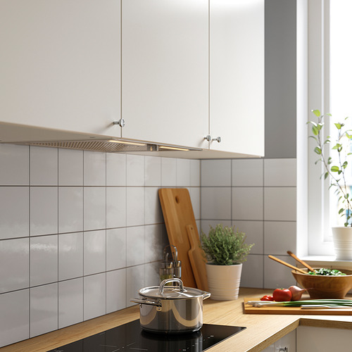Cocina moderna con gabinetes blancos, encimeras de madera, plantas.