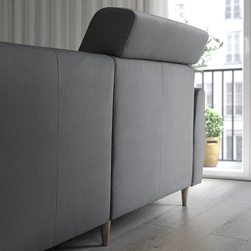 Un moderno sofá gris con cojines de respaldo extensibles para apoyar la cabeza. La foto muestra un diseño elegante y minimalista con patas de madera.