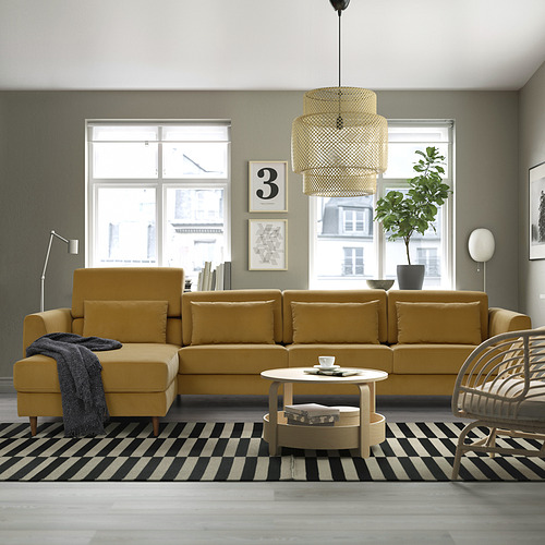 Sofá en forma de L amarillo mostaza con grandes cojines en amplia habitación.