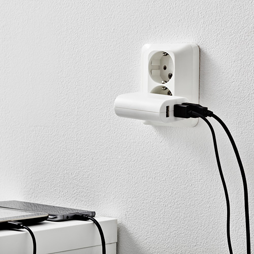 Un cargador de pared blanco con tres puertos usb, cargando un dispositivo negro, lo que demuestra su capacidad de carga multidispositivo.