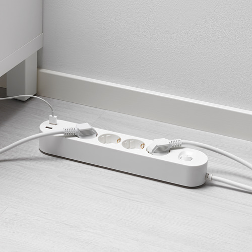 Multi-socket blanco con puertos usb sobre suelo de madera. Dos cables enchufados, uno con conector blanco.