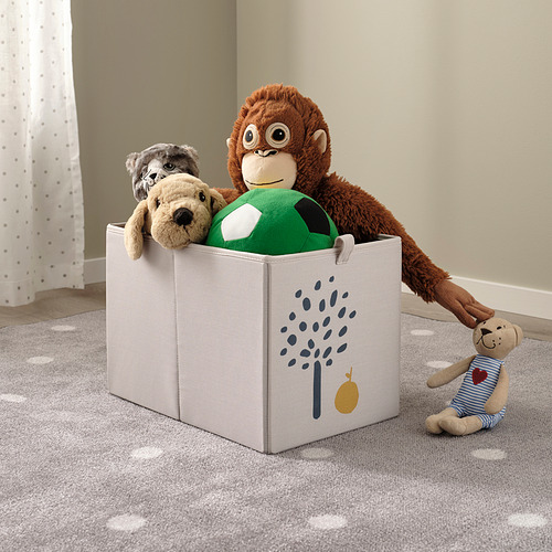Una caja de almacenamiento blanca con un estampado de árbol sostiene animales de peluche, y una muñeca de oso bebé está en el suelo junto a ella.