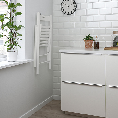 Cocina moderna con gabinete blanco, planta en maceta en el alféizar de la ventana y reloj montado en la pared.