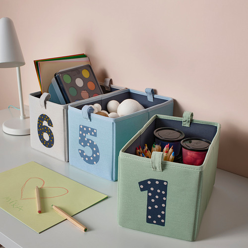 Cajas BARNDRÖM azules y verdes, numeradas, que contienen juguetes y suministros en un escritorio.