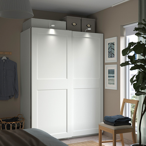 Dormitorio moderno armario PAX blanco con puertas correderas, que incluye cajas de almacenamiento y chaqueta colgante.