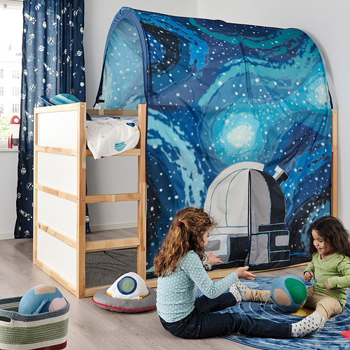Dos niños juegan bajo una cama de campaña con temática de galaxias azules unida a una litera de madera.