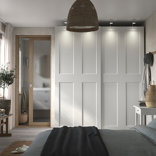 Dormitorio moderno con armario PAX blanco, ropa de cama gris, lámpara colgante de mimbre y detalles en madera.