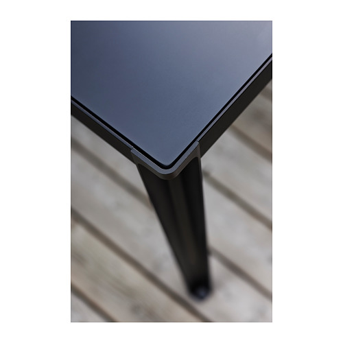 Pata de mesa oscura que soporta el tablero de la mesa cuadrada.