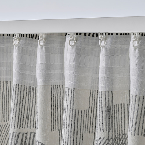 Las cortinas blancas con patrón de boceto cuelgan con ganchos, mostrando la función de cinta de encabezado que permite un fácil plisado y colgar la barra de la cortina.
