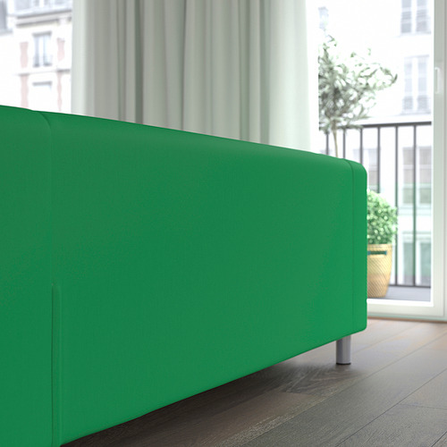 Sofá verde brillante cerca de la ventana, que ofrece asientos cómodos con funda duradera que se puede lavar a máquina.