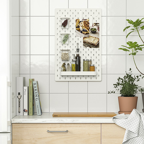 El tablero perforado blanco SKÅDIS organiza los artículos de cocina, incluidos frascos y cuadros, en la pared de azulejos, lo que ayuda a mantener los artículos cerca y accesibles.
