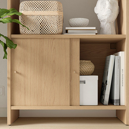 Armario LÅDMAKARE de madera clara con cestas tejidas y libros en la parte superior, con almacenamiento cerrado.