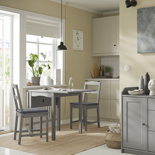 Acogedora zona de comedor con moderna mesa gris y sillas a juego, gran ventana, alfombra beige y decoración.