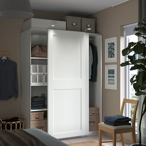 Dormitorio moderno con armario blanco, almacenaje gris y silla de madera.