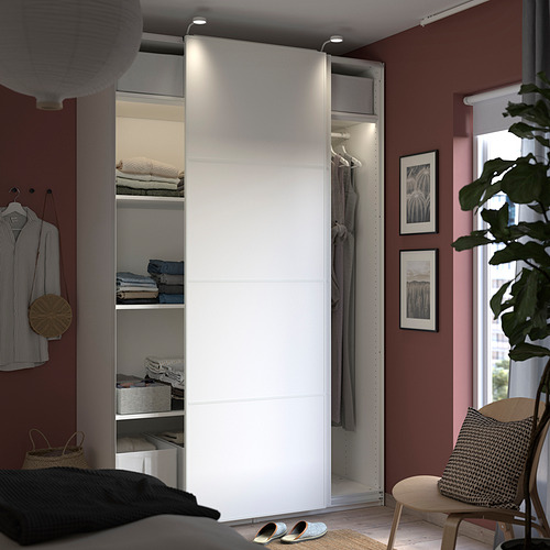 Dormitorio moderno con armario blanco y ropa organizada.