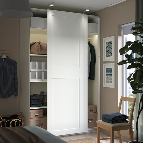 Dormitorio moderno con armario PAX blanco con puertas correderas y almacenamiento organizado, que incluye estantes y cajones.