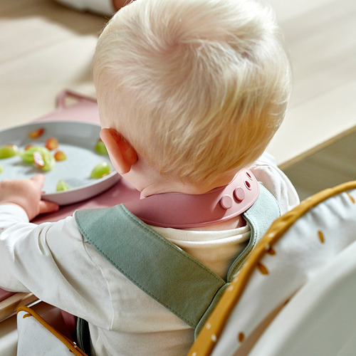 Bebé en silla alta con babero de silicona con un bolsillo para atrapar la comida, evitando ensuciar la ropa.
