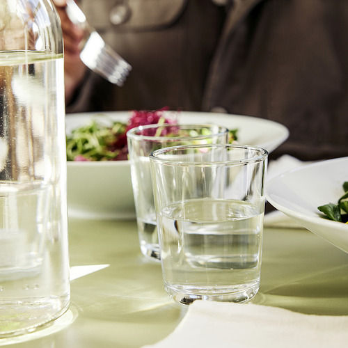 Mesa con vasos transparentes y jarra de agua, lista para la comida.