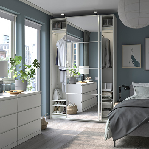 Dormitorio moderno con paredes grises, armario PAX blanco, puertas con espejos. Cama acogedora, alfombra, plantas grandes junto a la ventana.