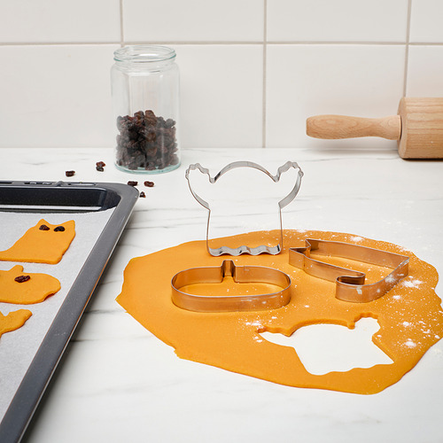 Cortadores de galletas en mostrador con masa y chispas de chocolate.