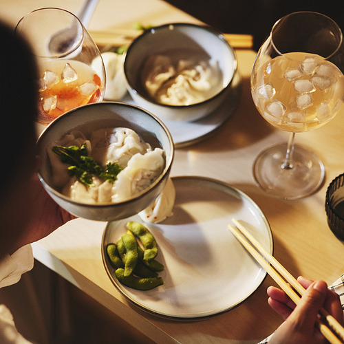 Dos copas de vino con bebidas, cuencos de albóndigas y wasabi, palillos en un plato.