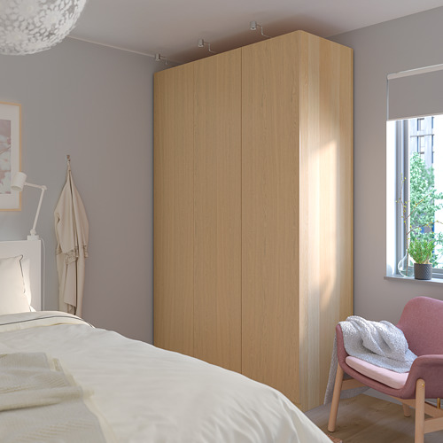 Gran armario PAX de madera contra la pared, con percheros, silla, cama y ventana.