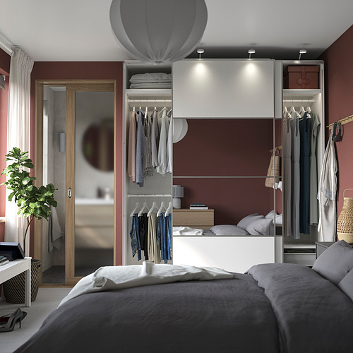 Dormitorio moderno con armarios PAX en blanco y burdeos, cama con ropa de cama gris y una planta.