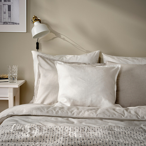 Cama con almohadas blancas DYTÅG, lámpara de pared, diseño sencillo y acogedor.