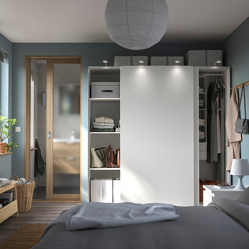 Dormitorio moderno con armario PAX blanco, puertas correderas, cama gris, suelos de madera, paredes azul verdosas y decoraciones colgantes.