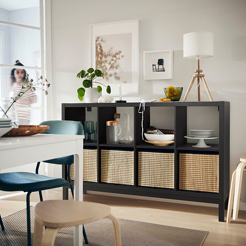 Sala de estar moderna Estantería negra KALLAX con inserciones tejidas, elementos decorativos y asientos elegantes.