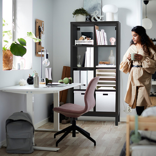 Mujer en la habitación con estante, silla, artículos de escritorio KALLAX. O, para una versión más concisa: mujer cerca de KALLAX escritorio con silla.