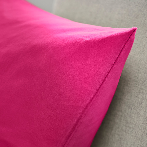 Funda de cojín de terciopelo rosa brillante, suave y lujosa, expuesta sobre una superficie gris.