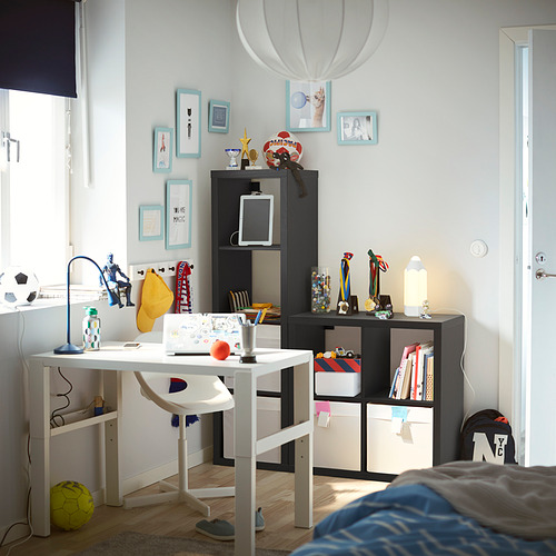 Una habitación para niños con una unidad de almacenamiento KALLAX blanca, llena de cajas de colores y premios.