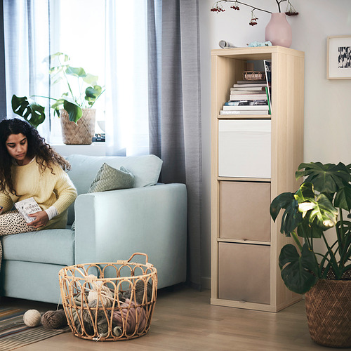 Acogedora sala de estar con sofá azul claro, estantería de madera KALLAX y mujer leyendo.