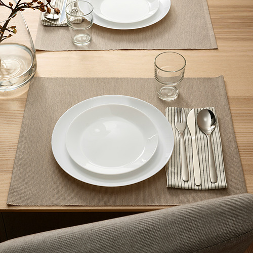 Dos juegos de mesa con platos, vasos y utensilios sobre manteles individuales y mesa beige.