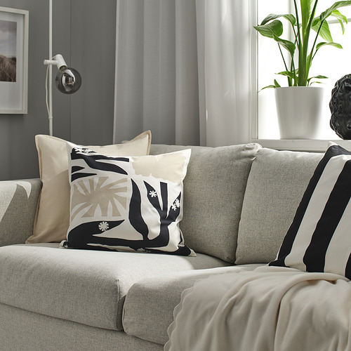 Sala de estar moderna con sofá gris, almohadas decorativas, almohada DRABOR en blanco y negro, planta verde, escultura abstracta, manta beige.
